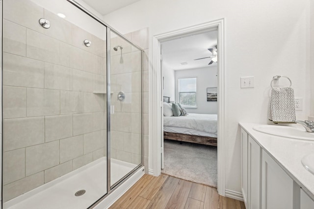 bathroom featuring ceiling fan, wood-type flooring, a shower with shower door, and vanity