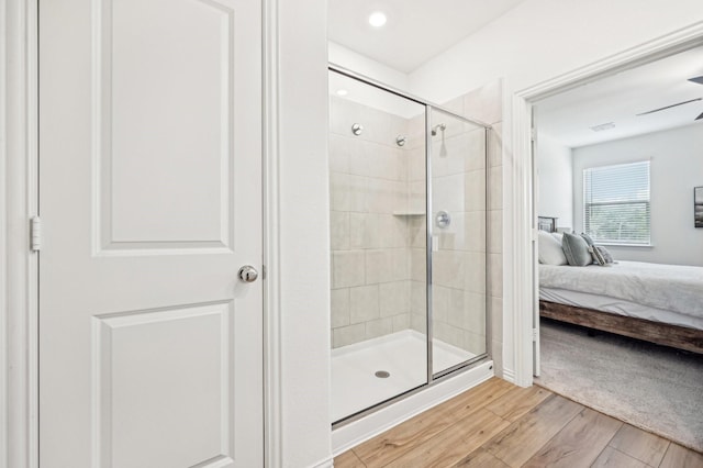 ensuite bathroom with visible vents, ensuite bathroom, wood finished floors, a shower stall, and ceiling fan