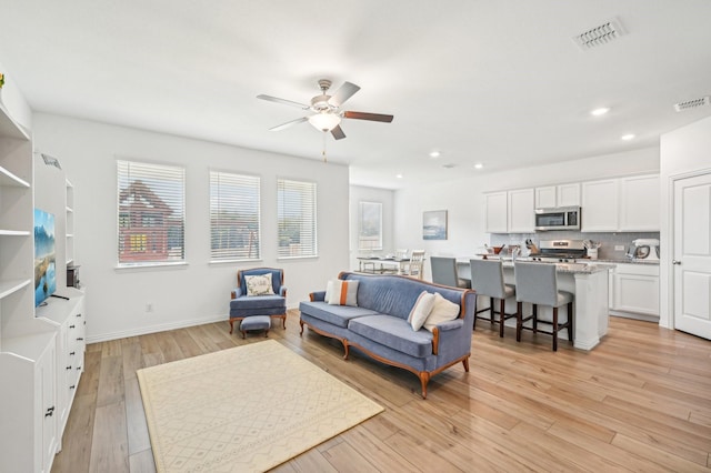 living room with light hardwood / wood-style flooring and ceiling fan