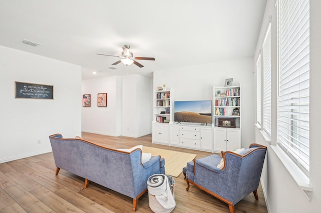 living room with visible vents, baseboards, light wood-style floors, and a ceiling fan