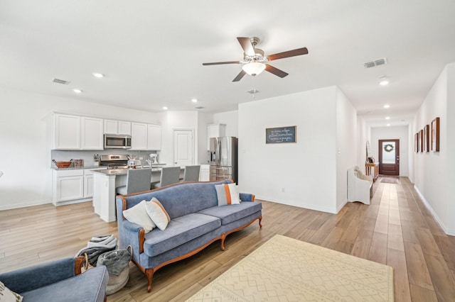 living room featuring recessed lighting, visible vents, light wood-style flooring, and baseboards