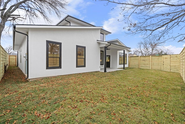 rear view of property featuring a lawn, a patio area, and ceiling fan