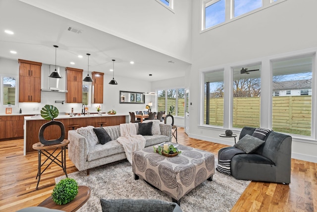 living room featuring sink, light hardwood / wood-style flooring, plenty of natural light, and ceiling fan