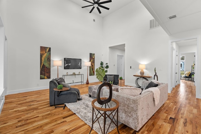 living room with ceiling fan, light hardwood / wood-style floors, and a high ceiling