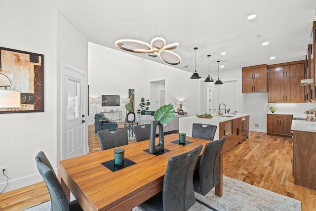 dining area featuring light wood-type flooring, a notable chandelier, and sink