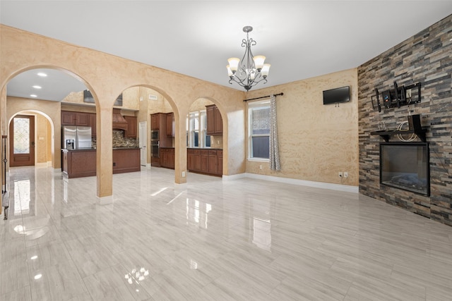 interior space with an inviting chandelier and a stone fireplace