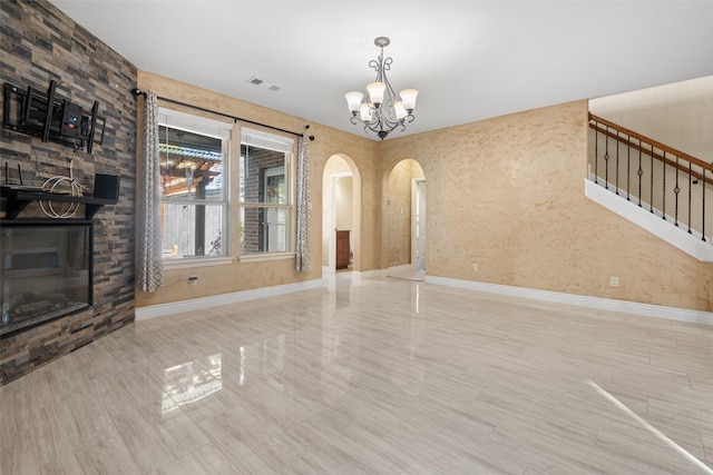 unfurnished living room with a large fireplace, light hardwood / wood-style flooring, and an inviting chandelier