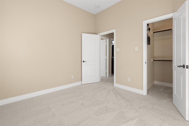 unfurnished bedroom featuring a walk in closet, light colored carpet, and a closet