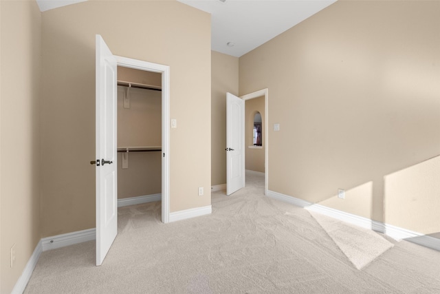 unfurnished bedroom featuring a walk in closet, light colored carpet, and a closet