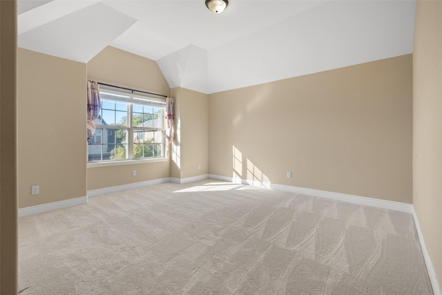 carpeted empty room with vaulted ceiling