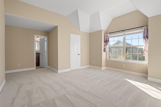 unfurnished bedroom with connected bathroom, light carpet, and lofted ceiling