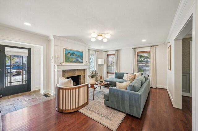 living room featuring a tile fireplace, crown molding, and dark wood-type flooring