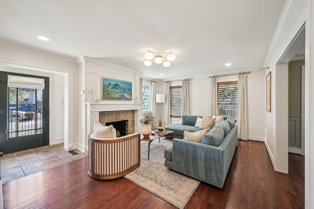 living room featuring a tiled fireplace, crown molding, and dark hardwood / wood-style floors