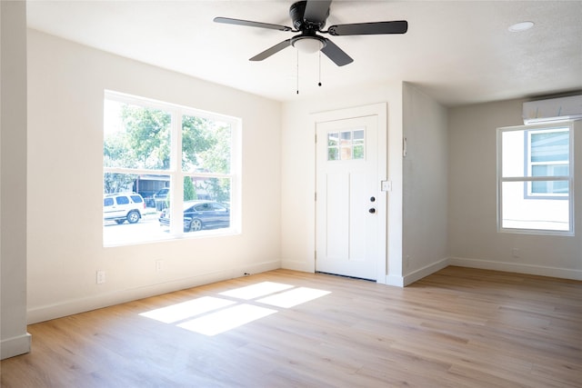 entryway with a wall mounted air conditioner, ceiling fan, and light wood-type flooring