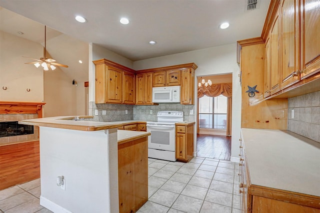 kitchen with kitchen peninsula, tasteful backsplash, white appliances, ceiling fan with notable chandelier, and light tile patterned flooring