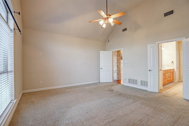 unfurnished bedroom featuring light colored carpet, high vaulted ceiling, ensuite bath, and ceiling fan