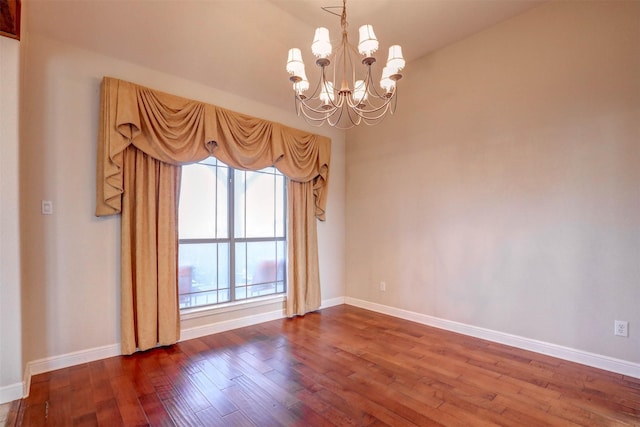 spare room with hardwood / wood-style flooring and an inviting chandelier