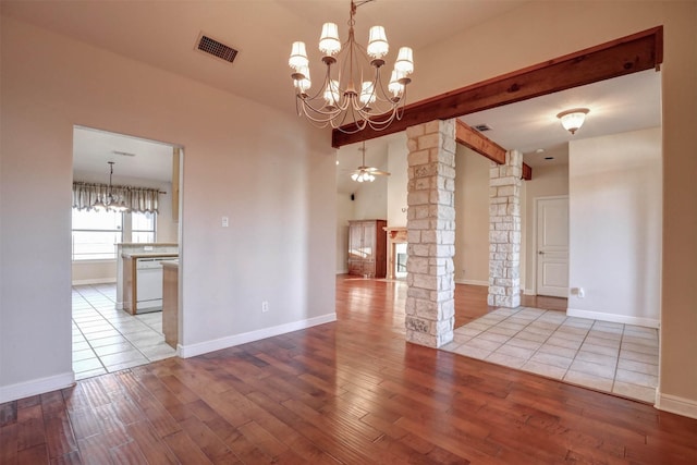 unfurnished room with light wood-type flooring, ceiling fan with notable chandelier, and decorative columns