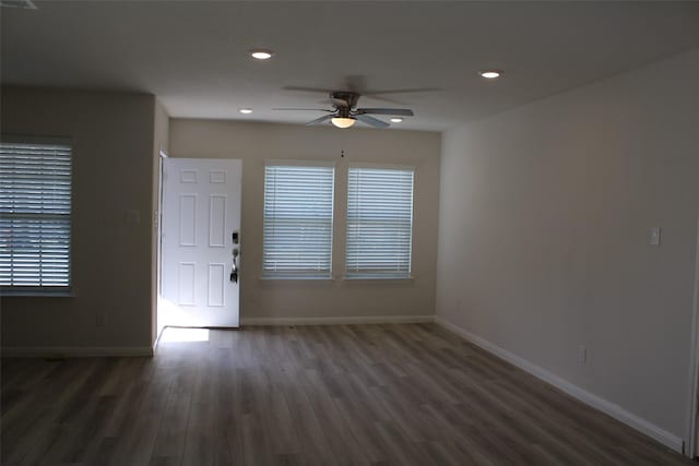 unfurnished room featuring a healthy amount of sunlight, ceiling fan, and dark wood-type flooring