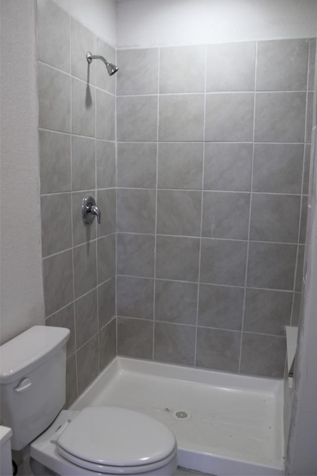 bathroom featuring tiled shower and toilet