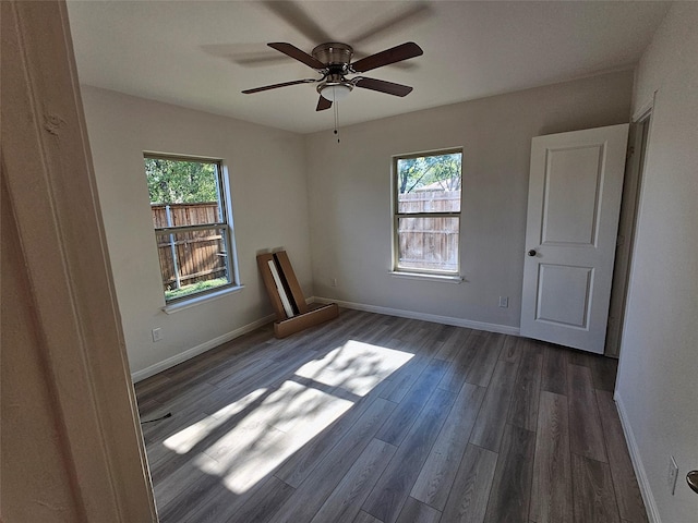 empty room featuring ceiling fan, dark hardwood / wood-style flooring, and a healthy amount of sunlight