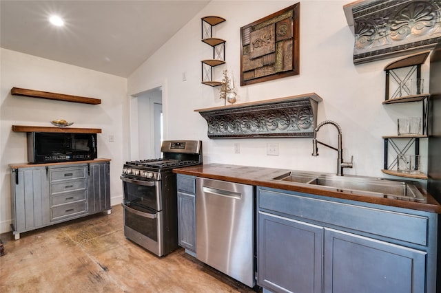 kitchen featuring lofted ceiling, butcher block counters, sink, gray cabinetry, and stainless steel appliances