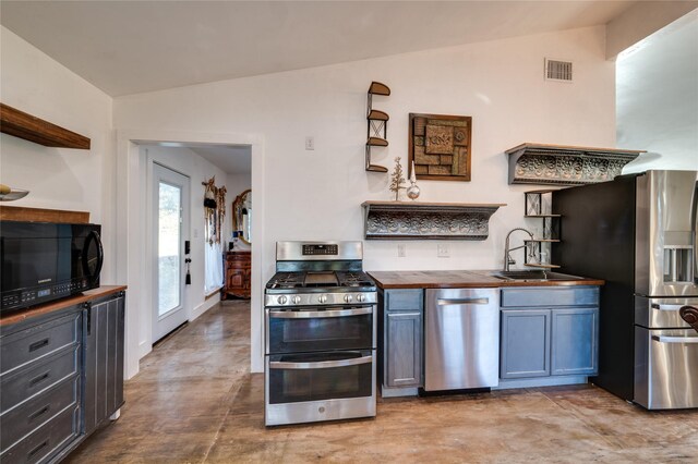 kitchen with stainless steel appliances, vaulted ceiling, sink, and wooden counters