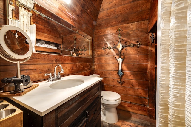 bathroom featuring vanity, wooden walls, and toilet