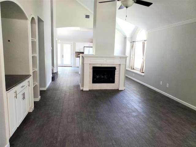 unfurnished living room featuring dark hardwood / wood-style flooring, ornamental molding, built in shelves, ceiling fan, and a fireplace