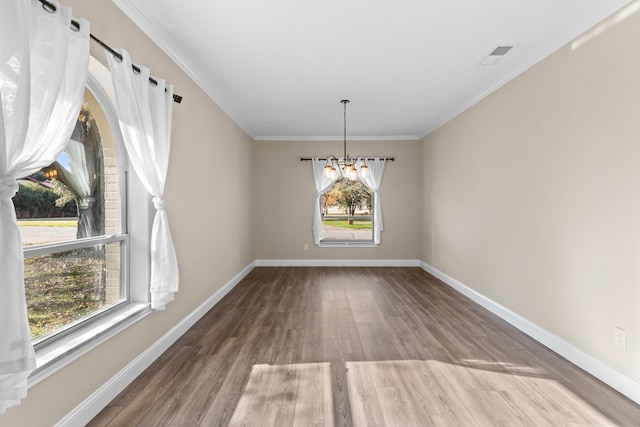 unfurnished dining area featuring crown molding, wood-type flooring, and an inviting chandelier