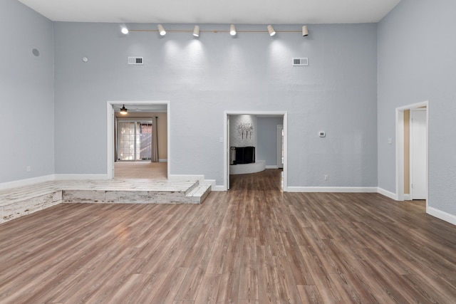 unfurnished living room featuring hardwood / wood-style flooring, a brick fireplace, and ceiling fan