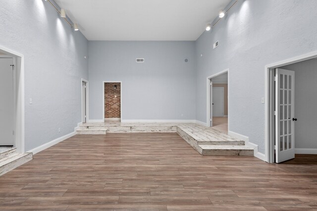 unfurnished living room with rail lighting and hardwood / wood-style flooring