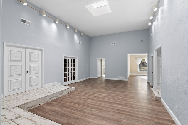 interior space featuring hardwood / wood-style floors, a towering ceiling, and a skylight