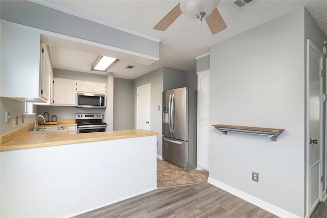 kitchen featuring sink, stainless steel appliances, kitchen peninsula, a textured ceiling, and white cabinets