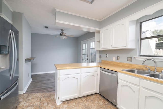 kitchen with sink, french doors, kitchen peninsula, white cabinets, and appliances with stainless steel finishes