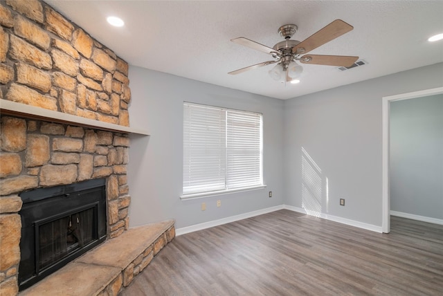 unfurnished living room featuring a fireplace, dark hardwood / wood-style flooring, and ceiling fan