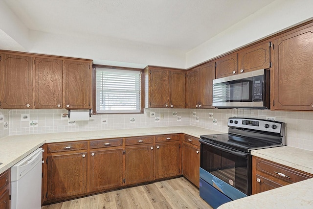 kitchen featuring white dishwasher, light wood-type flooring, black range with electric cooktop, and tasteful backsplash