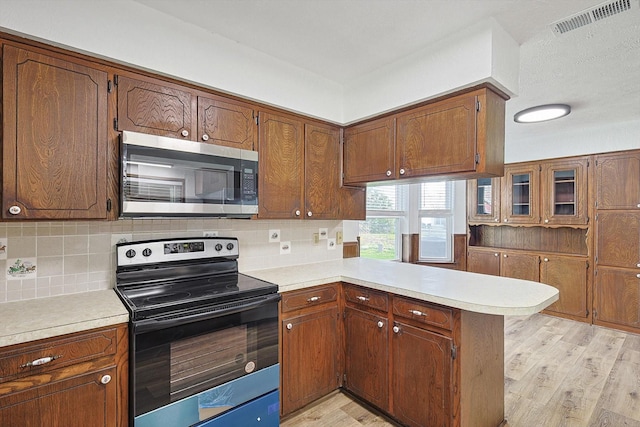 kitchen with tasteful backsplash, kitchen peninsula, electric range, and light hardwood / wood-style floors