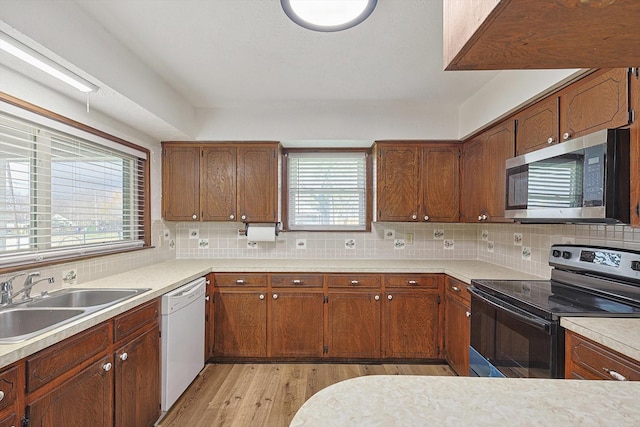 kitchen featuring decorative backsplash, appliances with stainless steel finishes, light wood-type flooring, and sink