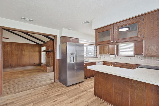 kitchen with sink, lofted ceiling with beams, kitchen peninsula, stainless steel fridge, and light hardwood / wood-style floors