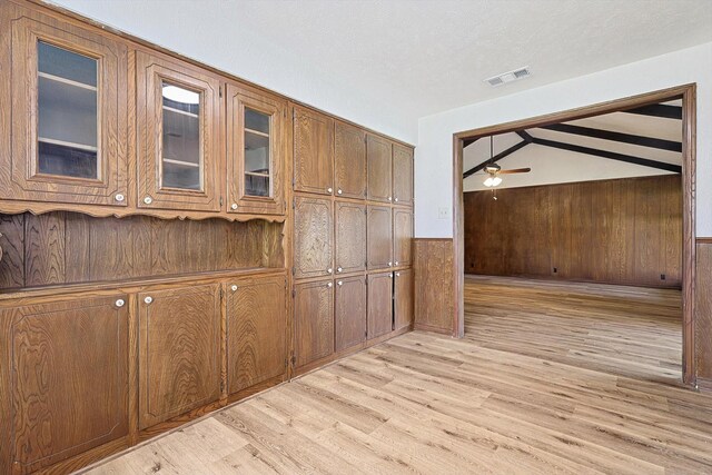 interior space featuring vaulted ceiling with beams, ceiling fan, light hardwood / wood-style floors, and wooden walls