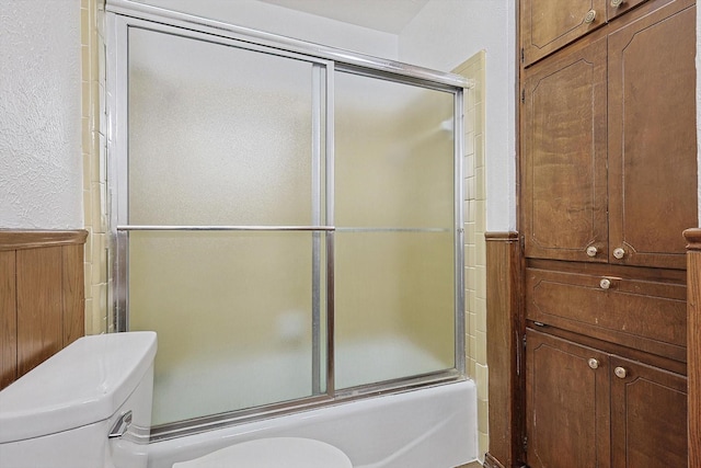 bathroom with shower / bath combination with glass door and toilet