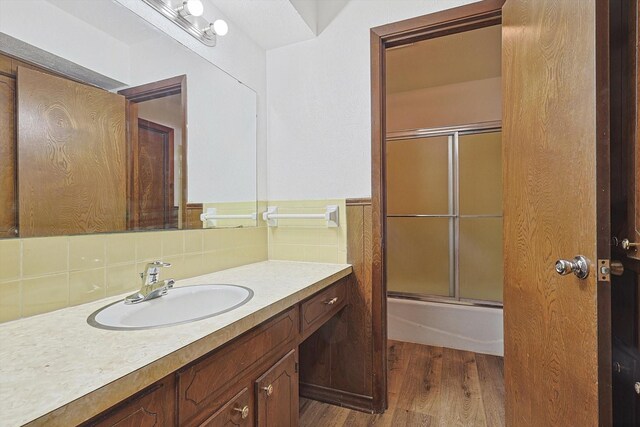 bathroom with tasteful backsplash, shower / bath combination with glass door, vanity, and wood-type flooring