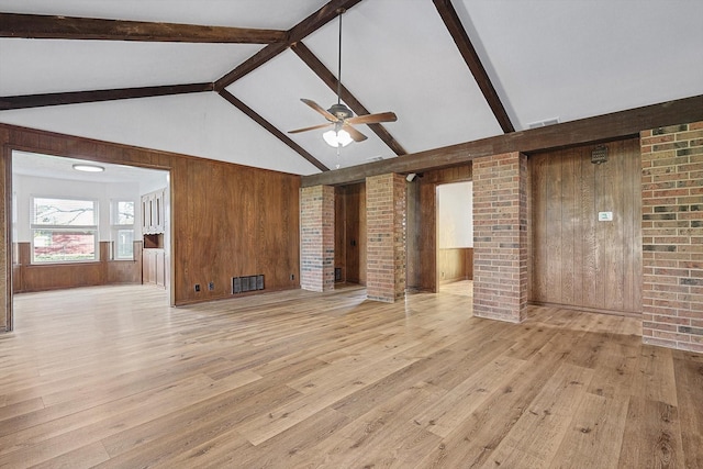 unfurnished living room featuring beamed ceiling, decorative columns, ceiling fan, and wood walls