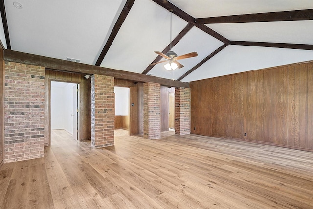 unfurnished living room featuring beamed ceiling, ceiling fan, wood walls, and light hardwood / wood-style floors