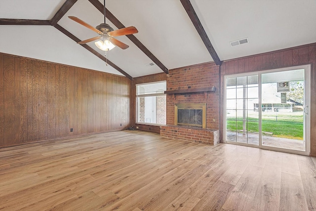 unfurnished living room featuring wood walls, beam ceiling, and a fireplace