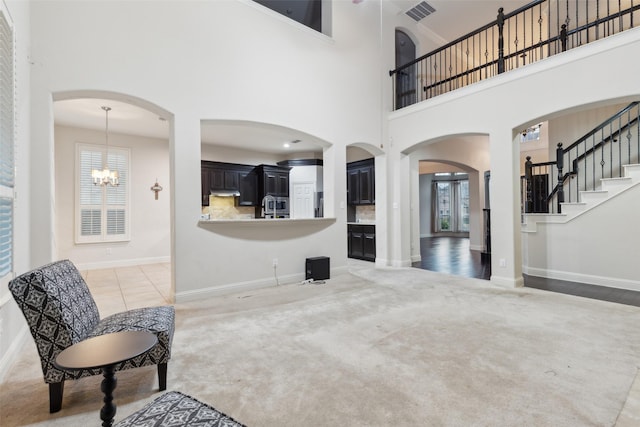 carpeted living room featuring a towering ceiling, a wealth of natural light, and a chandelier