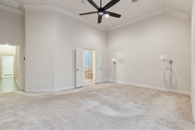 empty room with a high ceiling, crown molding, carpet floors, and ceiling fan