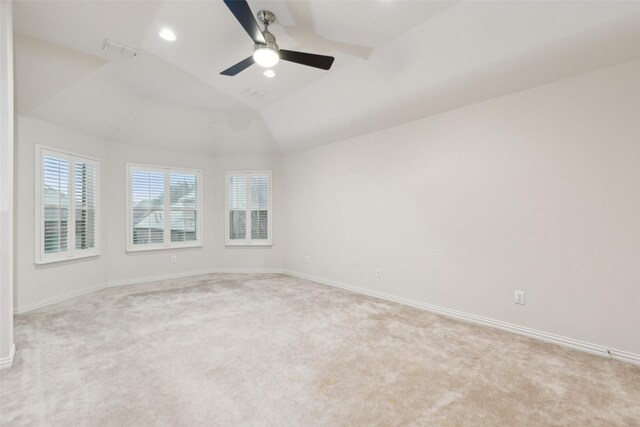 carpeted spare room featuring vaulted ceiling and ceiling fan