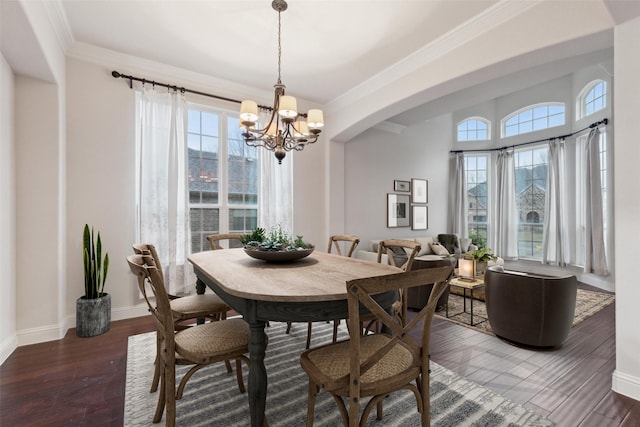 dining room with dark wood-type flooring, crown molding, and an inviting chandelier